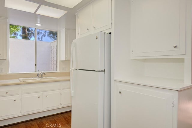 kitchen with white cabinets, dark wood-type flooring, sink, and white fridge