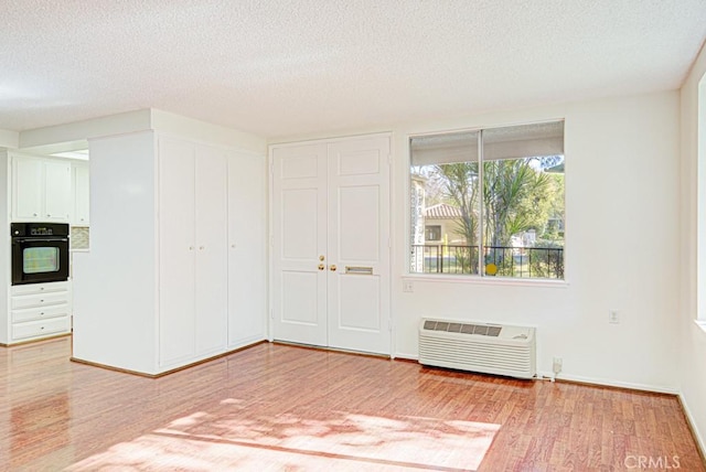 spare room featuring a textured ceiling, a wall mounted AC, and hardwood / wood-style flooring