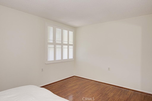 unfurnished bedroom with wood-type flooring and a textured ceiling