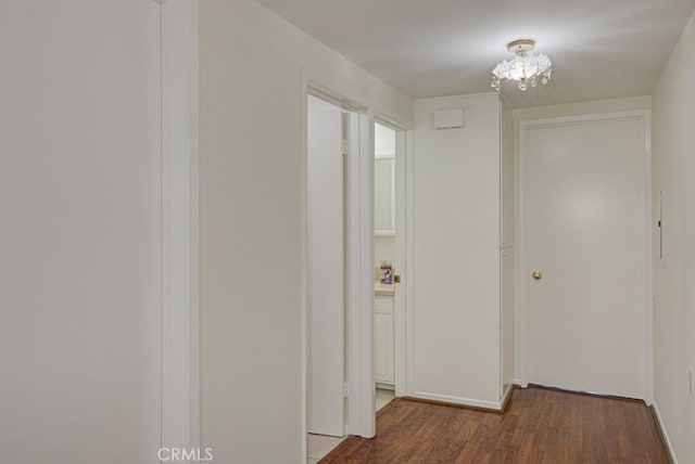 hallway with dark hardwood / wood-style floors and a chandelier