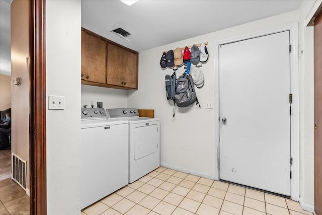 laundry room with cabinets, washing machine and dryer, and light tile patterned flooring