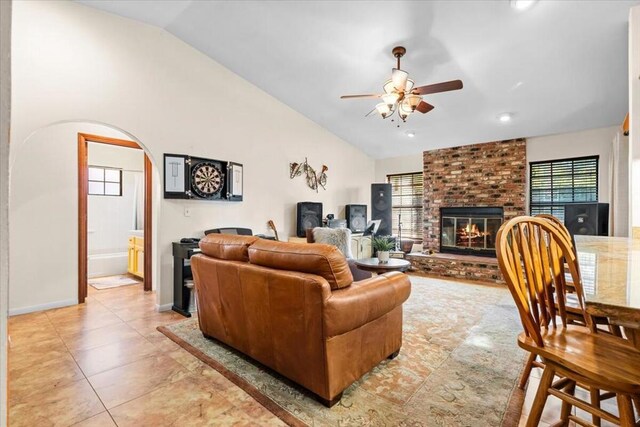 living room featuring ceiling fan, light tile patterned flooring, lofted ceiling, and a fireplace