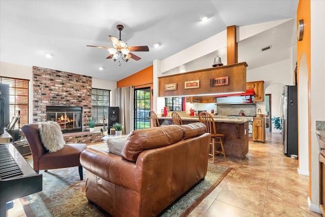 tiled living room with lofted ceiling, ceiling fan, and a fireplace