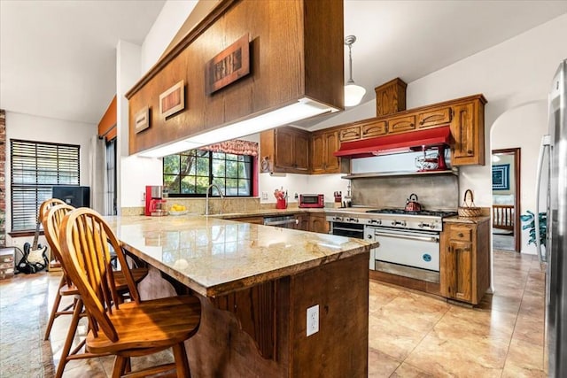 kitchen with lofted ceiling, pendant lighting, a breakfast bar, kitchen peninsula, and appliances with stainless steel finishes