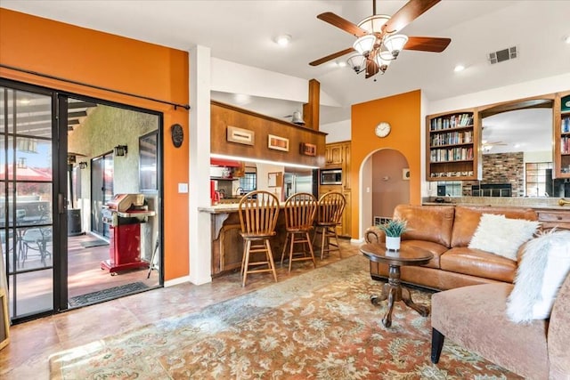 living room with ceiling fan, lofted ceiling, and a brick fireplace