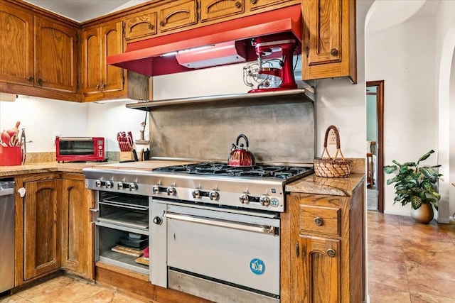 kitchen with light stone countertops, appliances with stainless steel finishes, and custom range hood