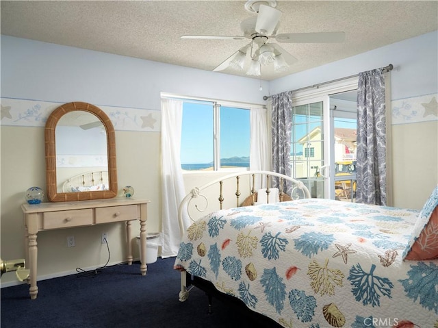 bedroom featuring ceiling fan, dark carpet, and a textured ceiling