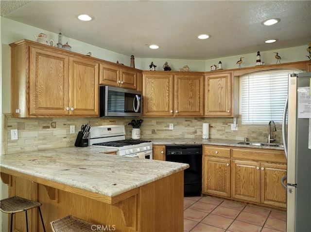 kitchen with light tile patterned floors, appliances with stainless steel finishes, a sink, a peninsula, and a kitchen breakfast bar