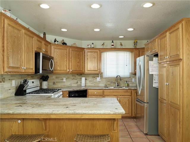 kitchen with light tile patterned flooring, a peninsula, a sink, appliances with stainless steel finishes, and decorative backsplash