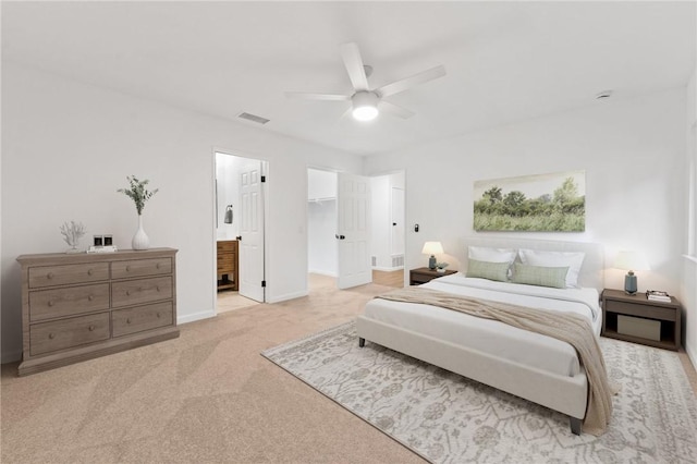 bedroom with light carpet, a walk in closet, ensuite bath, ceiling fan, and a closet