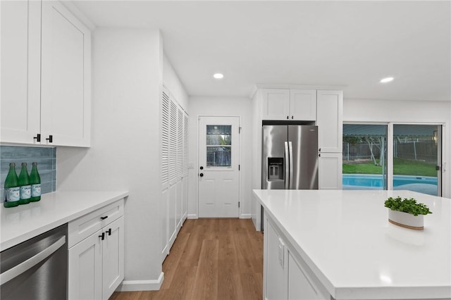 kitchen with white cabinets, stainless steel appliances, and light hardwood / wood-style flooring