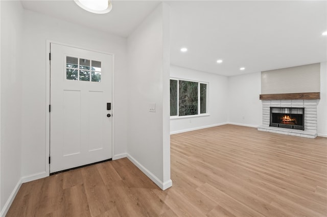 foyer with light wood-type flooring and a brick fireplace