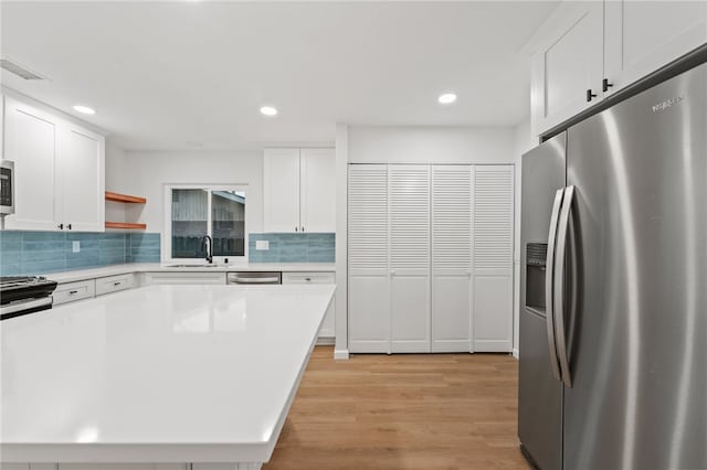 kitchen with sink, white cabinets, light hardwood / wood-style flooring, and appliances with stainless steel finishes