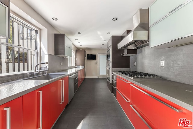 kitchen with appliances with stainless steel finishes, sink, backsplash, and wall chimney range hood