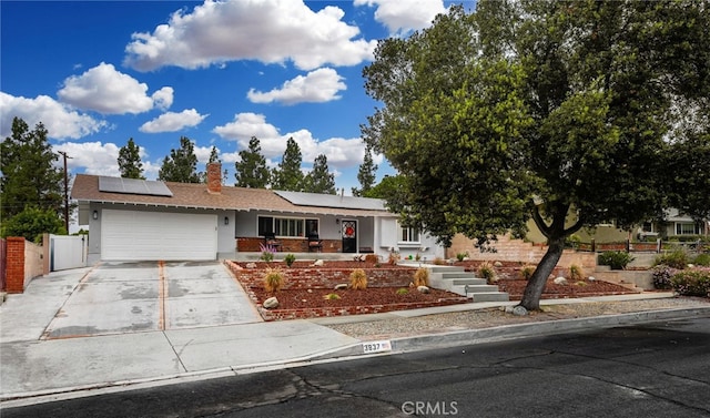 single story home featuring solar panels and a garage