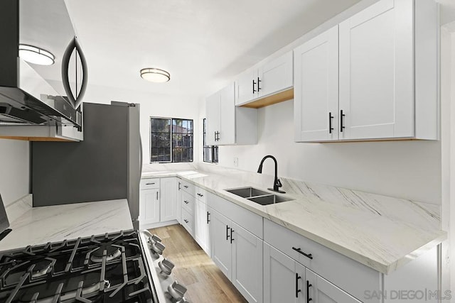 kitchen with white cabinets, light stone counters, and sink