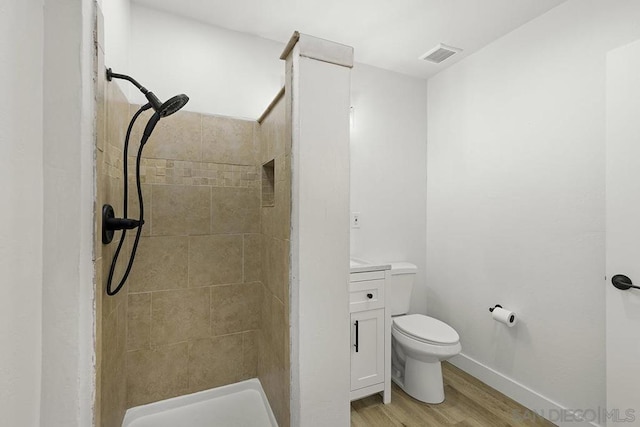 bathroom featuring toilet, vanity, tiled shower, and hardwood / wood-style flooring