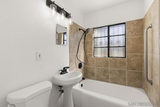 bathroom with toilet and tiled shower / bath