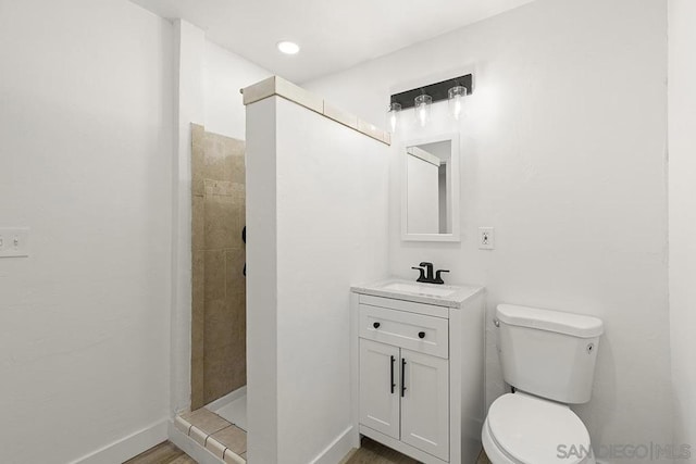 bathroom featuring tiled shower, vanity, and toilet