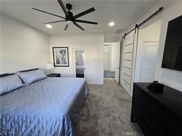 bedroom with ensuite bathroom, ceiling fan, carpet, and a barn door