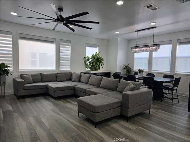 living room featuring ceiling fan with notable chandelier and wood-type flooring