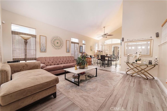 living room featuring high vaulted ceiling, ceiling fan, and light wood-type flooring