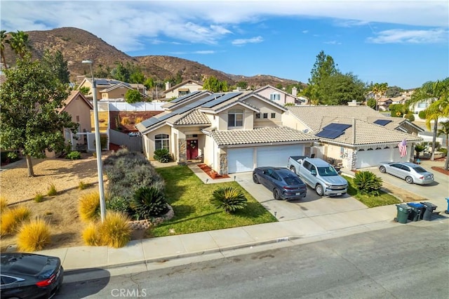 view of front of house with a garage, a mountain view, and solar panels