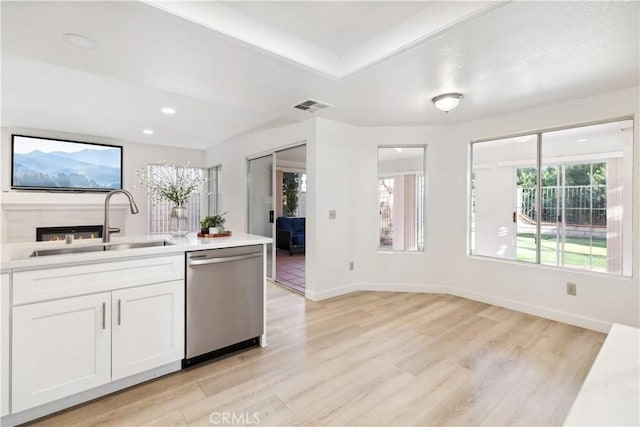 kitchen featuring sink, stainless steel dishwasher, white cabinets, and light wood-type flooring