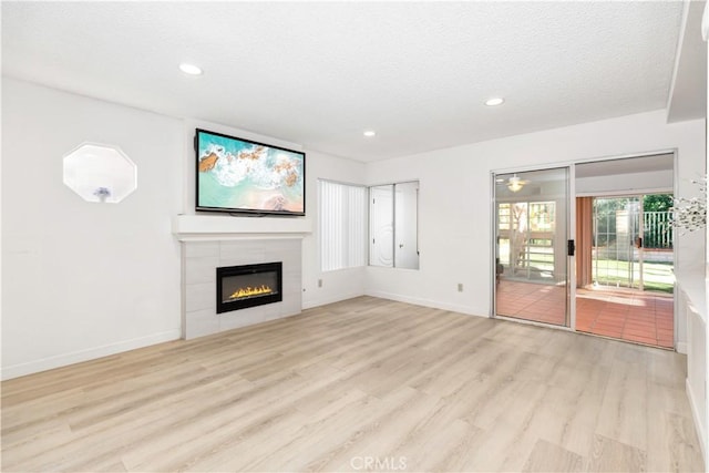 unfurnished living room with a textured ceiling, a fireplace, and light hardwood / wood-style flooring