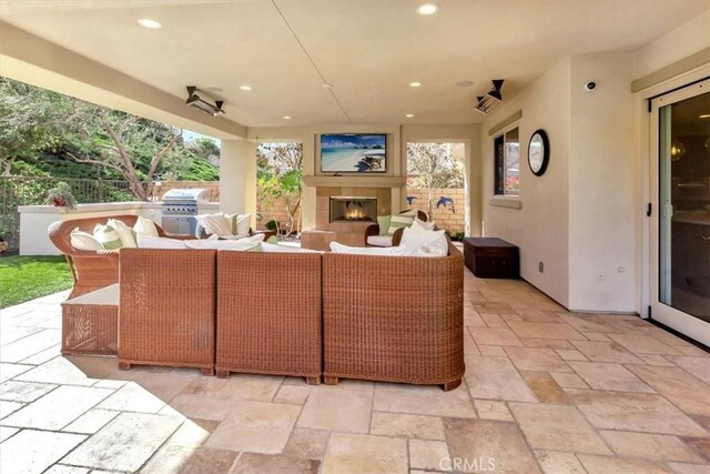 view of patio with an outdoor living space with a fireplace and area for grilling