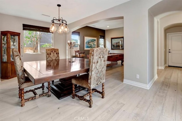 dining space with arched walkways, light wood finished floors, visible vents, an inviting chandelier, and baseboards