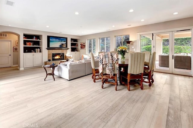 dining room featuring light wood-type flooring, a fireplace, built in features, and recessed lighting