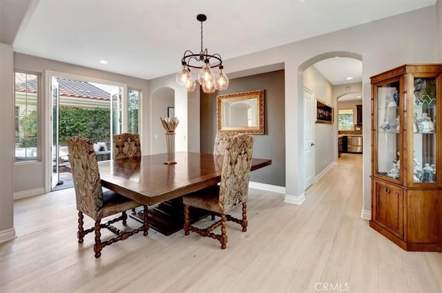 dining room featuring light wood-type flooring, arched walkways, baseboards, and recessed lighting