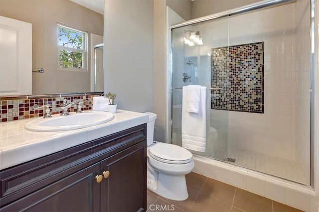 bathroom featuring backsplash, toilet, vanity, a shower stall, and tile patterned floors