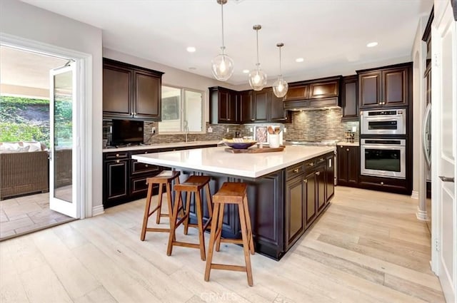 kitchen featuring hanging light fixtures, dark brown cabinetry, light countertops, and a center island