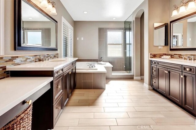 bathroom with vanity, decorative backsplash, and plus walk in shower