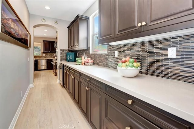 bar with arched walkways, plenty of natural light, backsplash, and stainless steel dishwasher