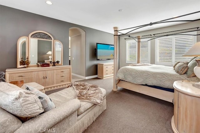 carpeted bedroom featuring baseboards and arched walkways