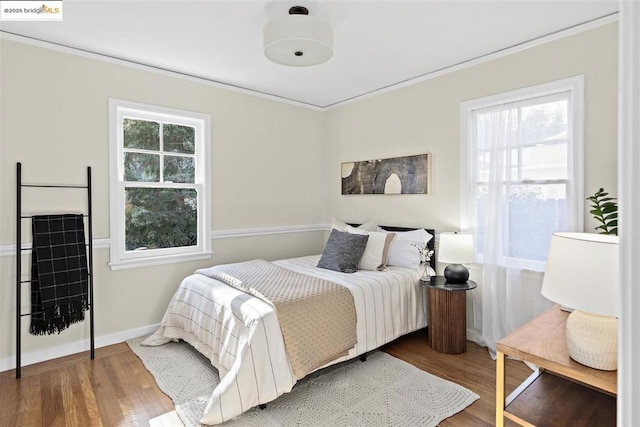 bedroom featuring ornamental molding, wood-type flooring, and multiple windows