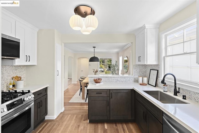 kitchen with light hardwood / wood-style floors, appliances with stainless steel finishes, pendant lighting, white cabinets, and sink