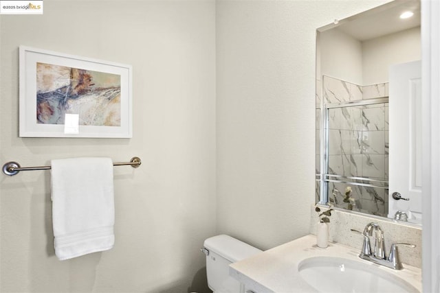 bathroom featuring toilet, a shower with door, and vanity