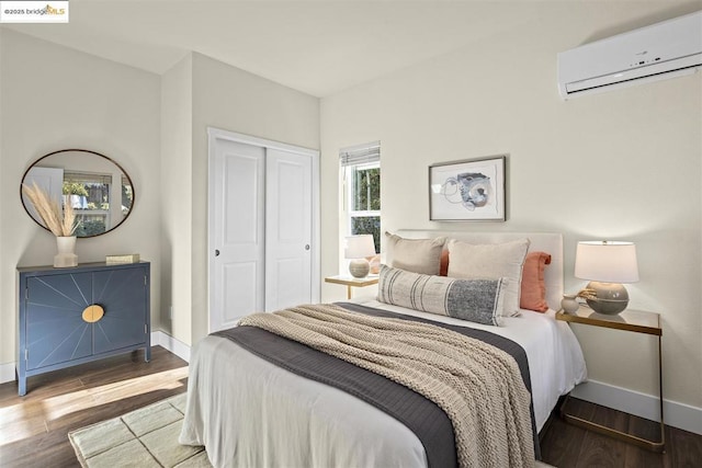 bedroom featuring hardwood / wood-style floors, a closet, and a wall unit AC