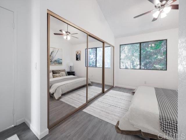 bedroom with ceiling fan, a closet, dark wood-type flooring, and vaulted ceiling