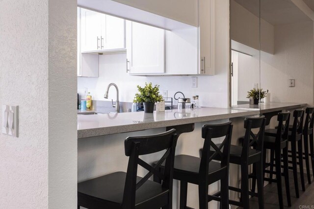 kitchen with a kitchen bar, white cabinets, and sink