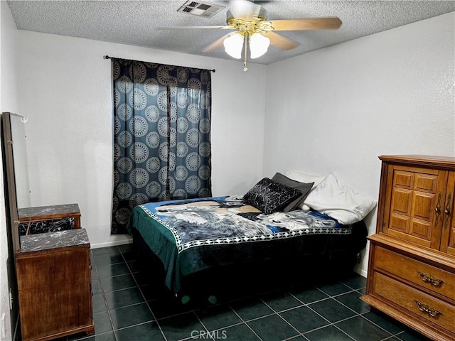 bedroom featuring a textured ceiling, ceiling fan, and dark tile patterned flooring