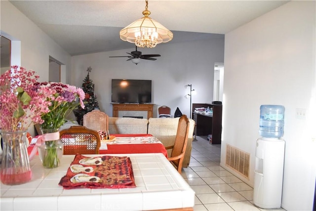 tiled dining area featuring ceiling fan with notable chandelier and vaulted ceiling