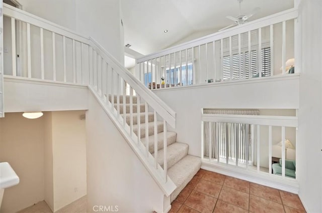 staircase with ceiling fan, tile patterned flooring, and vaulted ceiling