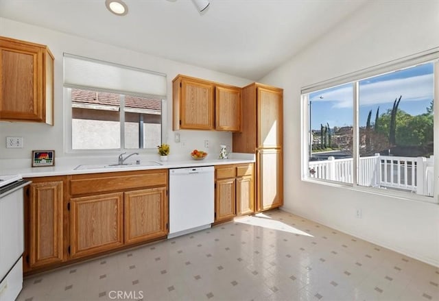 kitchen featuring stove, lofted ceiling, dishwasher, and sink