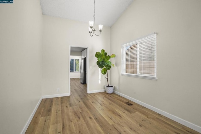 unfurnished room featuring a chandelier and light hardwood / wood-style floors