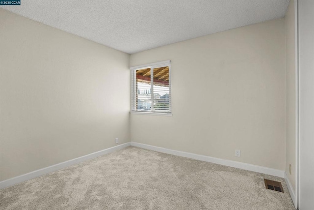 carpeted spare room featuring a textured ceiling